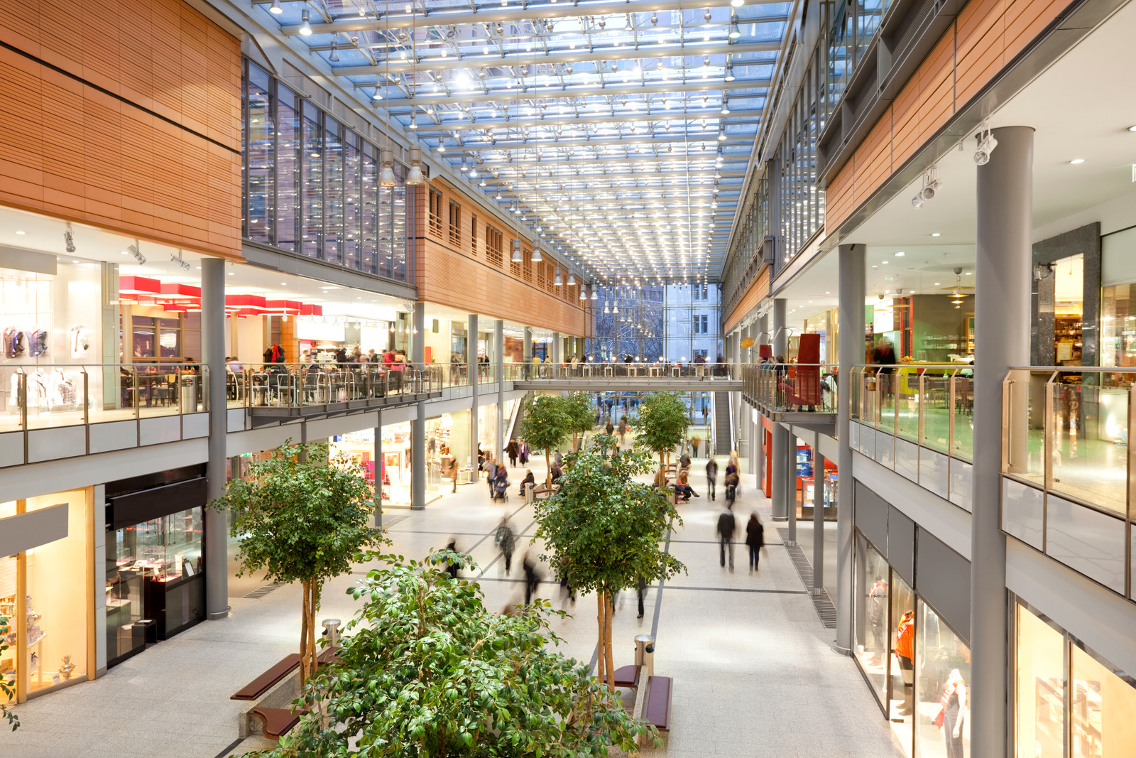 Image taken inside a shopping mall. There are lots of people walking around going to stores, buying things and consuming food and beverages. There are two floors with shops and boutiques. The ceiling is glass. The architecture is very modern and new and the general feel of the images is bright, clean, safe and positive. | Retail air conditioning