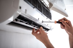Electrician repairing air conditioner indoors | air conditioning repair manchester